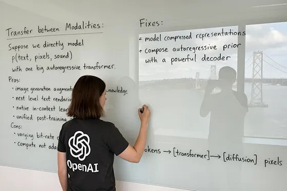A wide image taken with a phone of a glass whiteboard, in a room overlooking the Bay Bridge. The field of view shows a woman writing, sporting a tshirt wiith a large OpenAI logo. The handwriting looks natural and a bit messy, and we see the photographer's reflection.